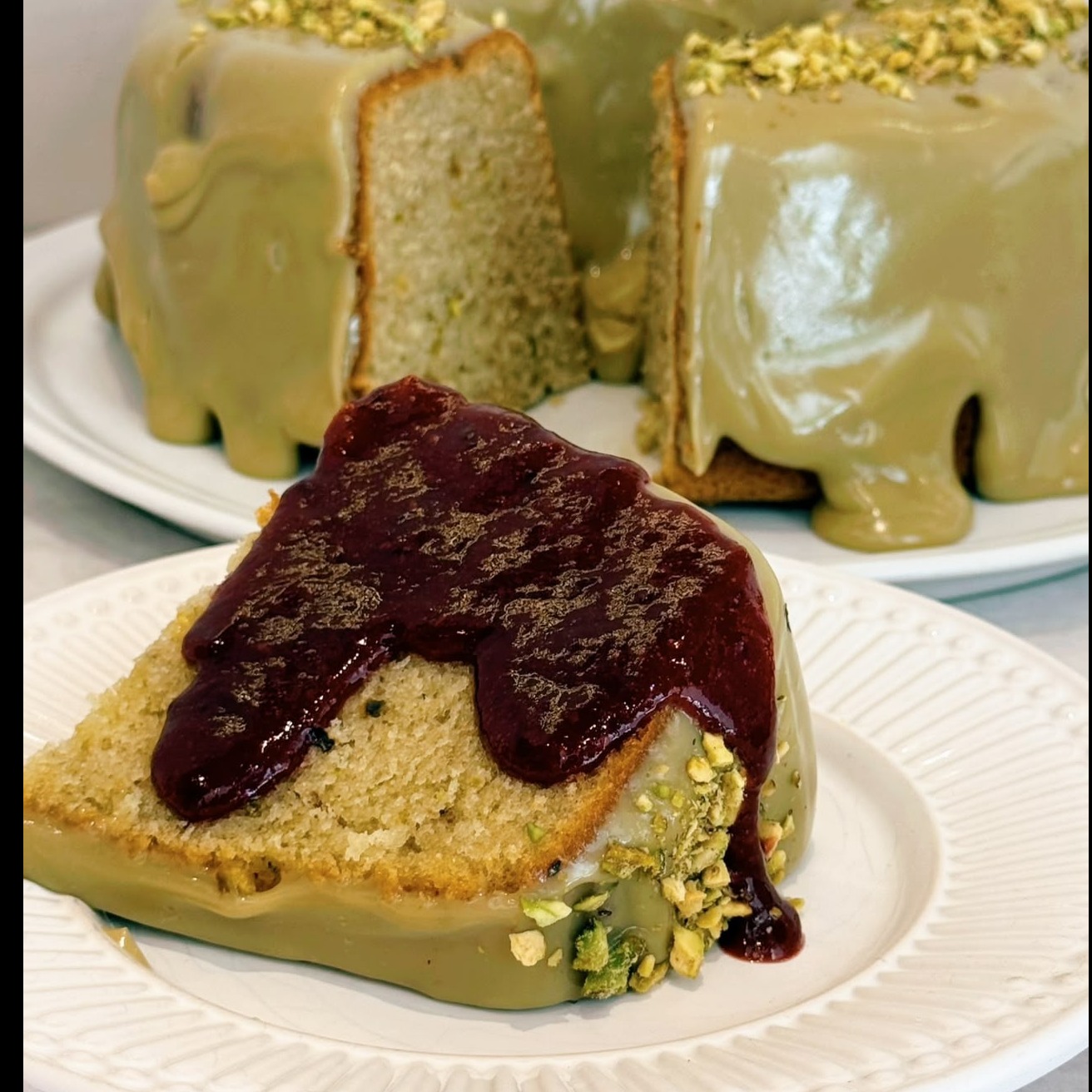 Fatia de bolo de pistache com calda de frutas vermelhas